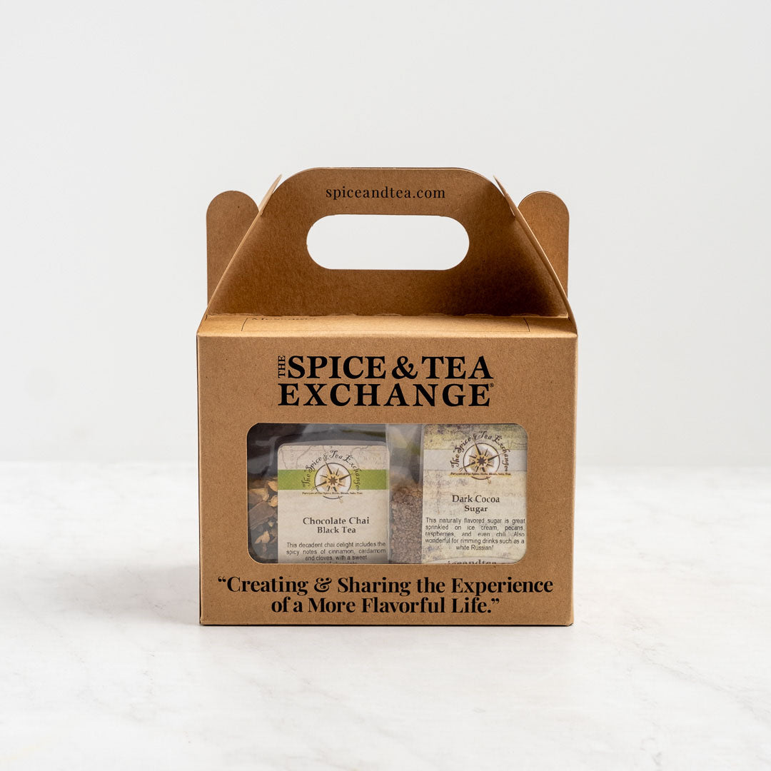 The Chocolate Lover's Gift Box is a brown cardboard box with a handle, labeled The Spice & Tea Exchange, containing Chocolate Chai tea and Dark Cocoa sugar—perfect cocoa blends. Features the slogan: Creating & Sharing the Experience of A More Flavorful Life.